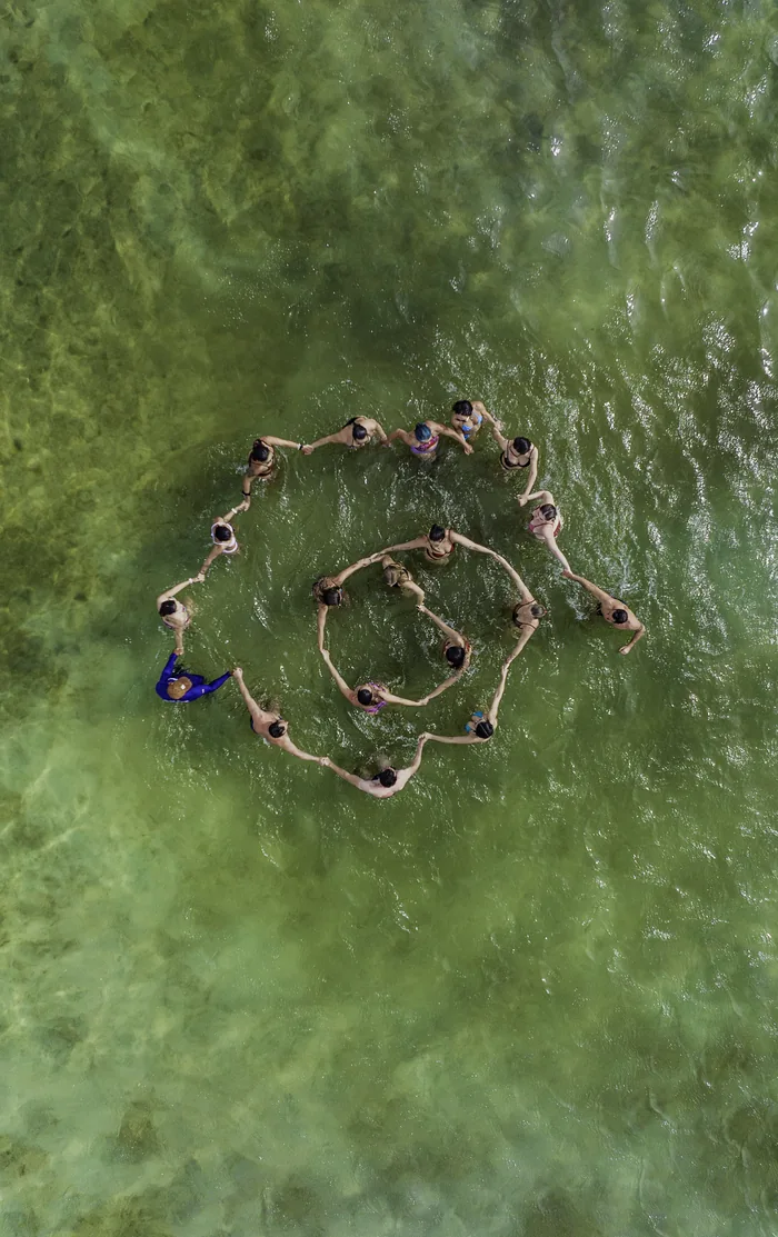 Grupo formando um círculo visto de cima nas águas verdes