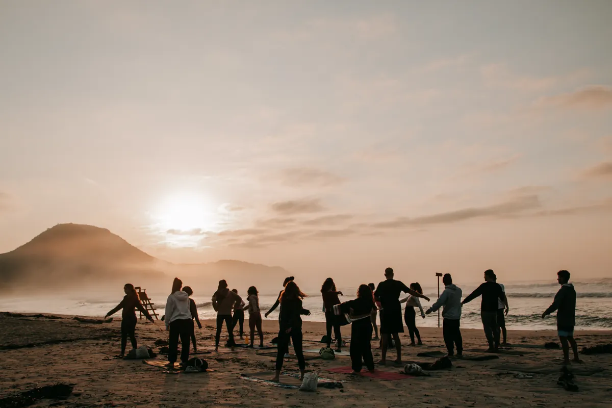 Grupo em roda na praia ao pôr do sol durante a jornada Eu, Oceano